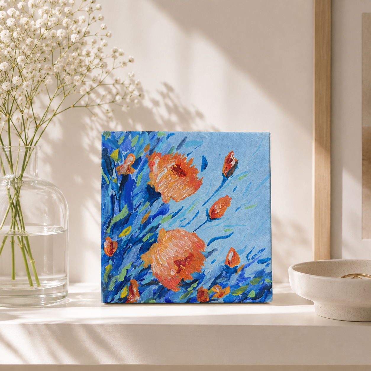 Floral painting on a light surface with a vase of flowers and a bowl in the background