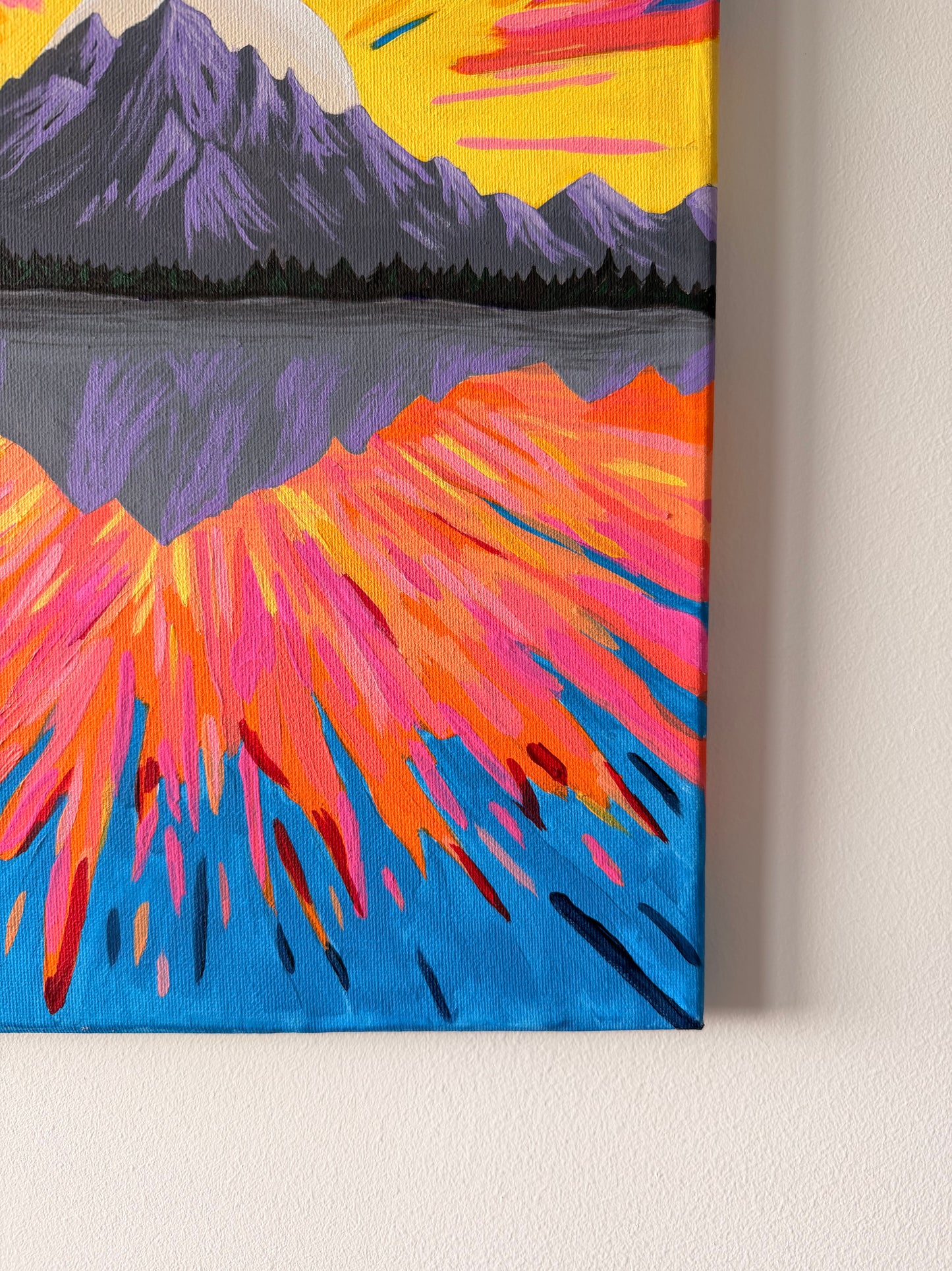 Colorful abstract painting of a mountain landscape on a beige wall.