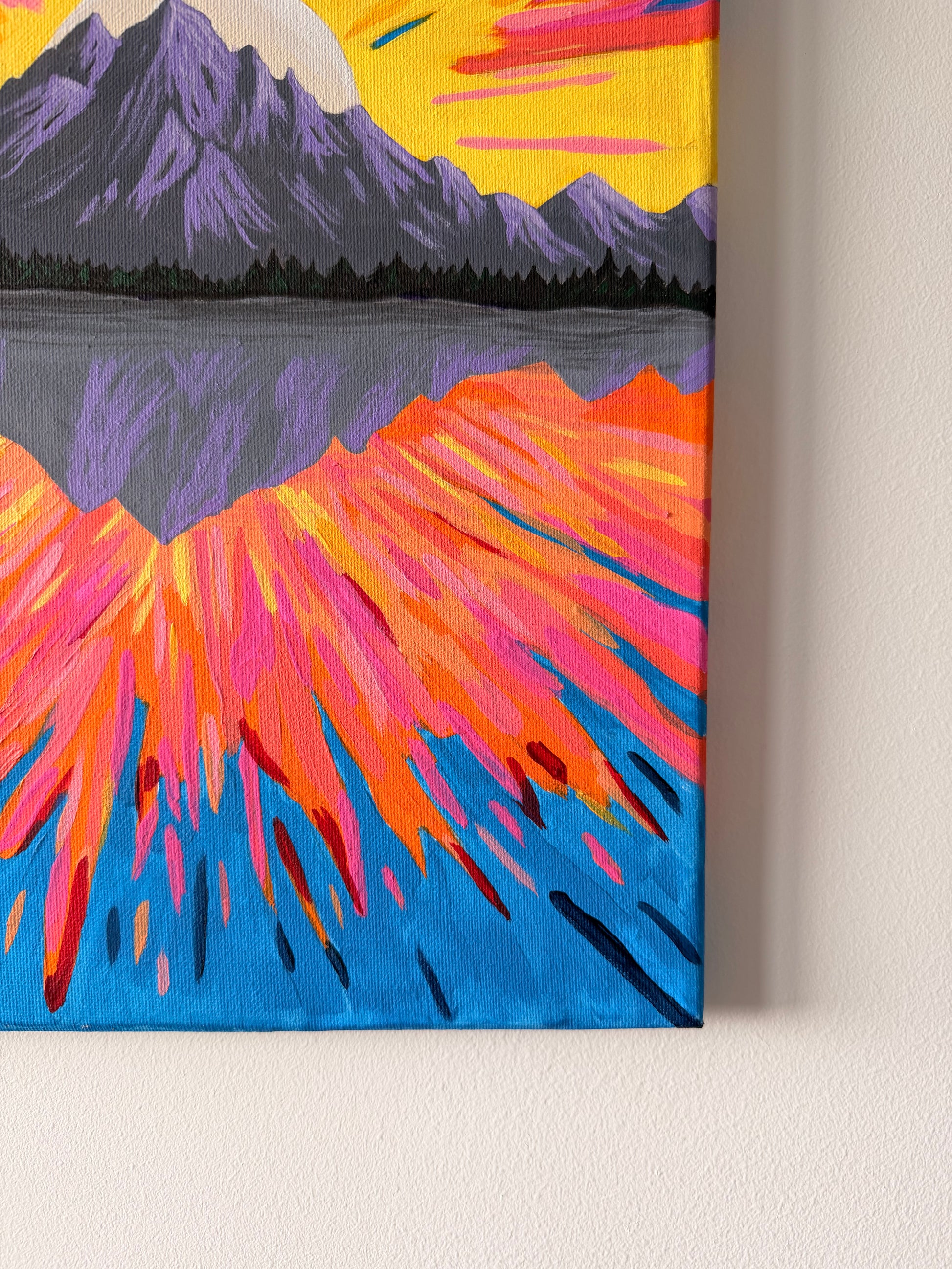 Colorful abstract painting of a mountain landscape on a beige wall.